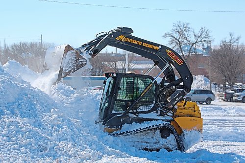 A compact track loader dumps snow into a pile in the parking lot of the Shoppers Drug Mart on Victoria Avenue on Monday afternoon. (Matt Goerzen/The Brandon Sun)