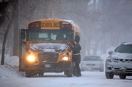 Brandon School Division bus driver Lori Snejdar cleans ice from the wiper blades of her school bus while waiting outside St. Augustine School on Wednesday afternoon. Rapidly deteriorating conditions on Wednesday prompted BSD to cancel bus service in rural areas. (Matt Goerzen/The Brandon Sun)