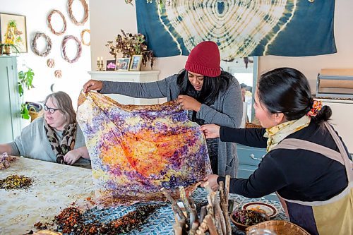 BROOK JONES / FREE PRESS
Lourdes Still (middle), who is the founder of Masagana Flower Farm, hosted a tinta experience workshop where participants were taught how to dye wearable fabric art at her studio in the RM of Ste. Anne, Man., Saturday, Feb. 24, 2024. Pictured: Free Press arts &amp; life writer AV Kitching (middle) and Still (right) look over the silk bandana Kitching dyed using dried flower blooms, while Colleen Dux (left) looks at her dyed silk bandana.