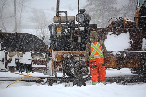 An employee with the Canadian National Railway watches a ballast regulator go over the rails after he has finished cleaning the tracks around a rail switch during Wednesday's snowstorm. The storm dumped more snow on the region only days after a weekend blizzard. (Matt Goerzen/The Brandon Sun)