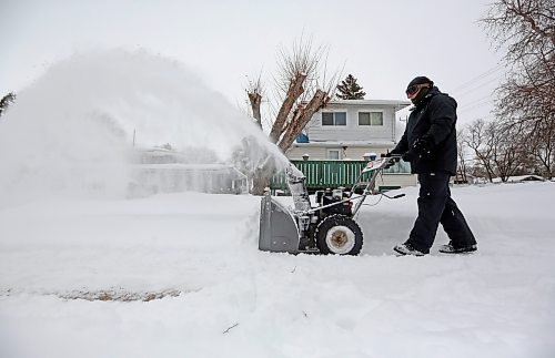 Brandon resident Kris Quiring blows the snow from the sidewalk in front of his neighbour's home in the 200 block of Percy Street on Thursday afternoon. (Matt Goerzen/The Brandon Sun)