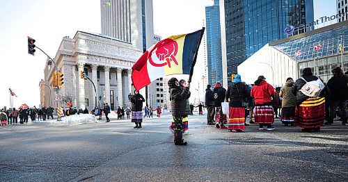 RUTH BONNEVILLE / FREE PRESS

Local Portage and Main Circle Dance 

A young person waves a large red power movement flag at the corner of Portage and Main as people prepare for a round dance Friday morning.  

AMC members and supporters form large circle surrounding the intersection of  Portage &amp; Main to form a Round Dance just prior to their march to the Legislative Building on International Women&#x573; Day. Friday morning.  

The Assembly of Manitoba Chiefs (AMC) host  a public event on March 8th, 2024, at 10:00 AM, ar Portage and Main to commemorate a National #SearchTheLandfill Day on this year&#x573; International Women&#x573; Day. 


March 8th , 2024
 