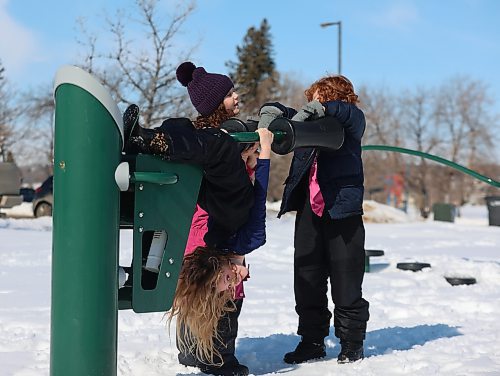 Seven-year-old Emilia Dixon hangs upside down on the exercise equipment at Brandon Riverbank Discovery Centre on a warm Monday afternoon, with her eight-year-old sister Isla (centre) and their six-year-old cousin Torrin Harding. (Michele McDougall/The Brandon Sun)