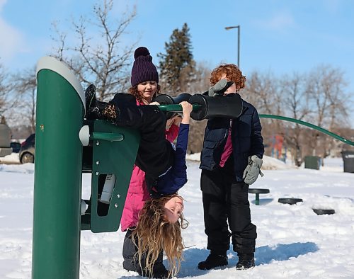 Seven-year-old Emilia Dixon hangs upside down on the exercise equipment at Brandon Riverbank Discovery Centre on a warm Monday afternoon, with her eight-year-old sister Isla (centre) and their six year old cousin Torrin Harding. (Michele McDougall/The Brandon Sun)