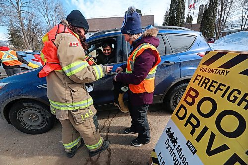 Brandon Fire & Emergency Services member Sarah Peto (left) works with fellow fundraiser Danna Twerdoski to find some change for a motorist who has just given a donation to the Brandon Firefighters Tri-Charity Rooftop Campout and Boot Drive on Friday afternoon. (Matt Goerzen/The Brandon Sun)