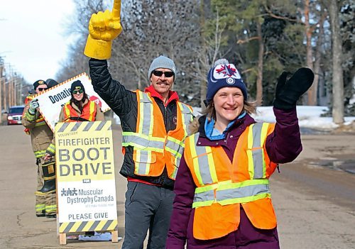Brandon Fire &amp; Emergency Services member Shayne Collister raises a big yellow hand behind fellow fundraiser Danna Twerdoski as they wave to passing motorists outside Brandon First Station 2 on 13th Street on Friday afternoon to help raise money for the last day of the Brandon Firefighter's Tri-charity Rooftop Campout and Boot Drive. The fundraising drive began March 12, with members camping for four days and three nights on the top of the firehall to raise money for Muscular Dystrophy, Cerebral Palsy and the Brandon Firefighter's Charity Fund. (Matt Goerzen/The Brandon Sun)
