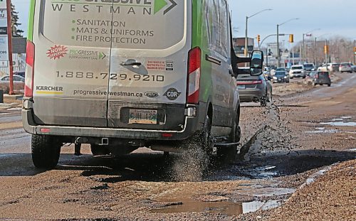 Unable to avoid them, a vehicle drives through a line of water-filled potholes on Richmond Avenue on Tuesday afternoon. (Matt Goerzen/The Brandon Sun)