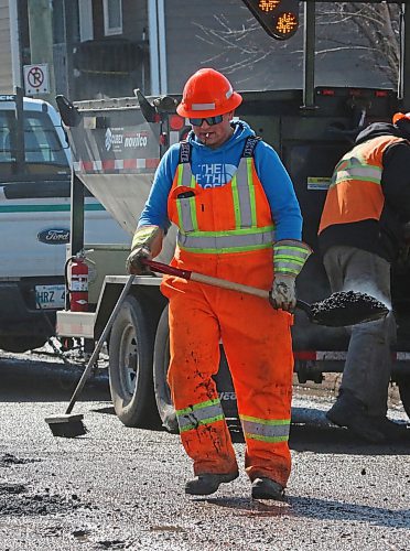 With the asphalt steaming in his shovel, an employee with Manitoba Transportation and Infrastructure walks to a pothole on First Street on Tuesday afternoon. The province had two road repair crews working on Tuesday, with one on First Street and the other on 18th Street. (Matt Goerzen/The Brandon Sun)