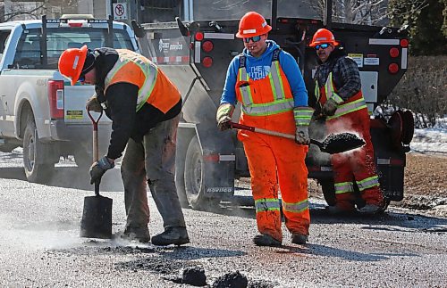 With steaming asphalt spilling out of his shovel, an employee with Manitoba Transportation and Infrastructure walks to a pothole on First Street on Tuesday afternoon. The province had two road repair crews working on Tuesday, with one on First Street and the other on 18th Street. (Matt Goerzen/The Brandon Sun)