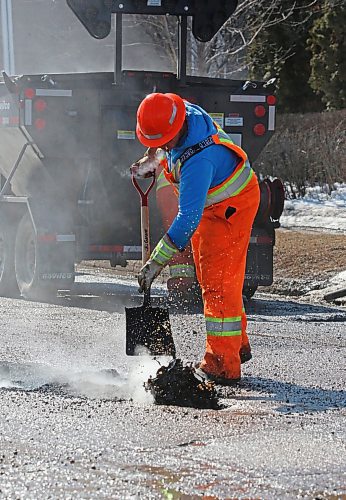 Dirty water flies out of a pothole after hot asphalt is tossed inside by a Manitoba Transportation and Infrastructure Department employee on First Street Tuesday afternoon. (Matt Goerzen/The Brandon Sun)