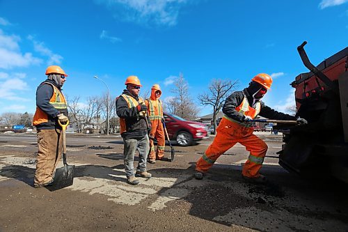 Crew members watch while a Manitoba Transportation and Infrastructure employee struggles to pull a shovel of cold pothole filler out of the back of a trailer on Tuesday afternoon. The crew was tasked with patching hundreds of potholes along the southbound lanes of 18th Street. (Matt Goerzen/The Brandon Sun)
