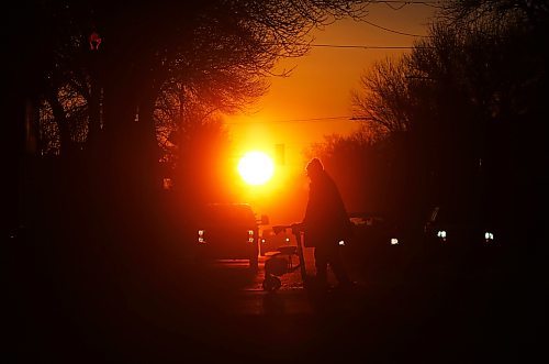 Silhouetted against the rising sun on the first day of the spring equinox, motorists wait at a stop light along Princess Avenue while a man with a walker crosses the street on Wednesday morning. (Matt Goerzen/The Brandon Sun).