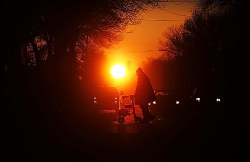 Silhouetted against the rising sun on the first day of the spring equinox, motorists wait at a stop light along Princess Avenue while a man with a walker crosses the street on Wednesday morning. (Matt Goerzen/The Brandon Sun). 