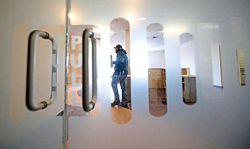 Seen through the front doors of the future home of Brandon's Food Rescue Grocery Store, Donovan Kimball, the store's logistics support, wields a drywall trowel as he helps ready the store for it's April 3 opening on Thursday afternoon. (Matt Goerzen/The Brandon Sun)