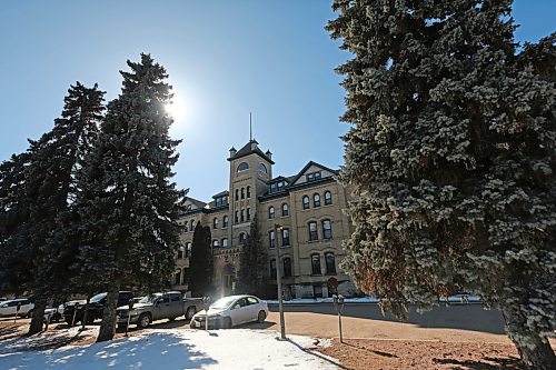 A bright sun peaks out from behind a fir tree in front of Brandon University's Clark Hall on Friday afternoon. After a strike was averted early this month, BU and its faculty association have reached a tentative agreement. Faculty will vote on it next week. (Matt Goerzen/The Brandon Sun)