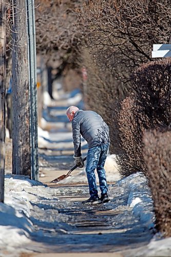 An area resident tries to break the ice on a sidewalk along Lorne Avenue with a garden spade on a sunny Friday afternoon. (Matt Goerzen/The Brandon Sun)