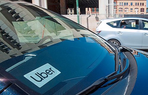 MIKE DEAL / WINNIPEG FREE PRESS
A taxi speeds by a vehicle with an Uber sticker in the window which is sitting outside City Hall for the announcement that the ride sharing service is open for business in Winnipeg as of today. 
200707 - Tuesday, July 07, 2020.