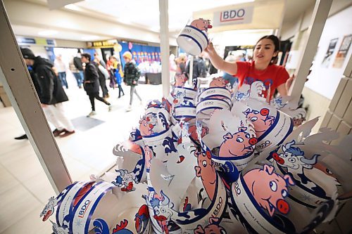 Royal Manitoba Winter Fair volunteer Alisha Ducharme stacks dozens of paper hats especially made for the fair by BDO outside the entrance to the Westoba Place Arena on Monday afternoon. (Matt Goerzen/The Brandon Sun)