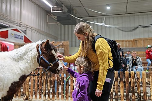 Courtney Bujold and daughter Claire pet Rollie the pony during an event at Flynn Arena on Tuesday at the Royal Manitoba Winter Fair. (Colin Slark/The Brandon Sun)