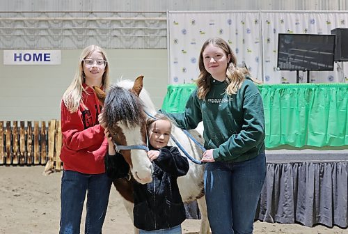 Leighton Wilts (right), Ilee Sturgeon (left) and Lexi Palmer (centre) hang out with Rollie the pony while volunteering for the Horse Power Reading Program at the Flynn Arena during the Royal Manitoba Winter Fair on Tuesday. (Colin Slark/The Brandon Sun)