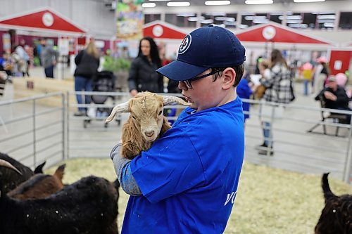A volunteer at the Royal Manitoba Winter Fair enjoys some time with a baby goat at the event's petting zoo on Tuesday. (Colin Slark/The Brandon Sun)