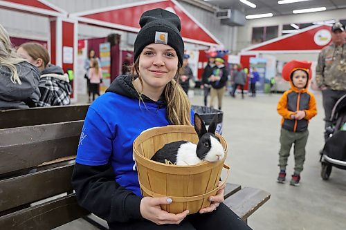 Volunteer Brooklyn Sabourin holds a basket containing a rabbit near the petting zoo section at the Royal Manitoba Winter Fair on Tuesday. (Colin Slark/The Brandon Sun)