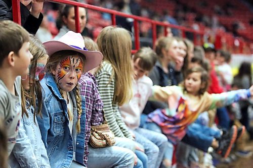 A girl with a painted face and a pink cowboy hat appears to whistle while sitting along the boards with a hundred other kids waiting for the WoofJocks show to begin on the opening night of the Royal Manitoba Winter Fair, Monday. (Matt Goerzen/The Brandon Sun)