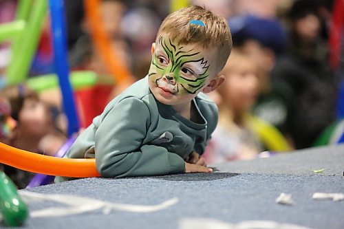 A young boy with a painted face and confetti in his hair leans on the stage during the Doodles the Clown show on Tuesday afternoon during the Royal Manitoba Winter Fair. (Matt Goerzen/The Brandon Sun)