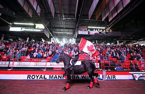 A flagbearer on horseback carries the Canadian flag around the Westoba Place Arena on Tuesday to start the evening show for the Royal Manitoba Winter Fair. (Matt Goerzen/The Brandon Sun)