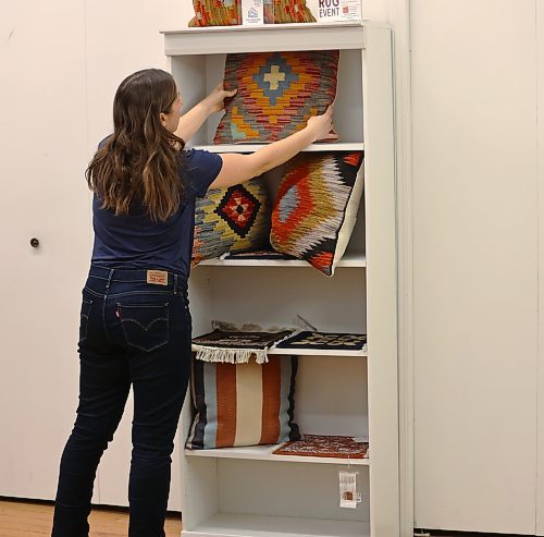 Stephanie De la Luz, store manager at Ten Thousand Villages, puts the finishing touches on the display of hand made and fair trade pillows for the store's upcoming Fair Trade Rug Event happening April 4 - 22, 2024 in Brandon. (Michele McDougall/The Brandon Sun)