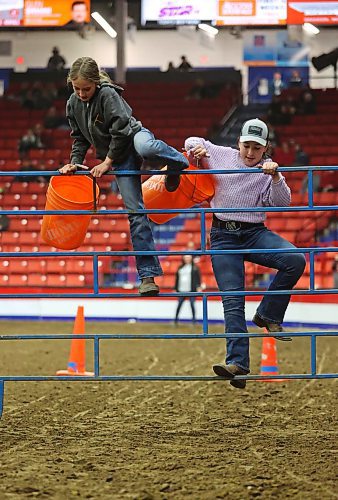 Pails in hand, Ryder Muir and Lilli Kulbacki clamber over a gate obstacle during hte Provincial Ex of Manitoba youth Obstacle Course on Wednesday evening during the Royal Manitoba Winter Fair. (Matt Goerzen/The Brandon Sun)