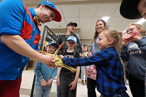 Jordan Sabo of JoJo's Magic Circus entertains a young girl named Shealyn and her family with a rubber chicken in the Keystone Centre hallway on Thursday afternoon during the Royal Manitoba Winter Fair. (Matt Goerzen/The Brandon Sun)