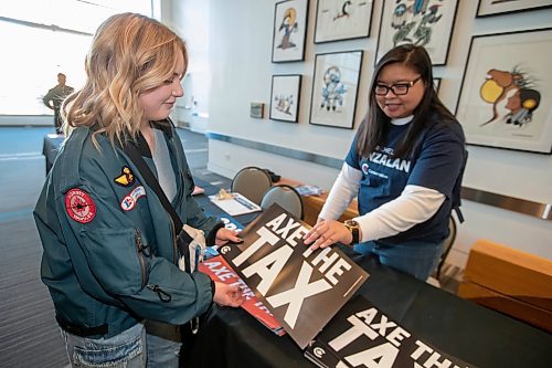 BROOK JONES / FREE PRESS
Cadence Cowel (left) 20, picks up an 'Axe the Tax' sign from Janice Wy, who is from Winnipeg North Conservative candidate Rachel Punzalan's team of supporters, during the Conservative Party of Canada Leader Pierre Poilievre's 'Spike the Hike - Axe the Tax' rally at the RBC Convention Centre in Winnipeg, Man., Thursday, March 28, 2024.