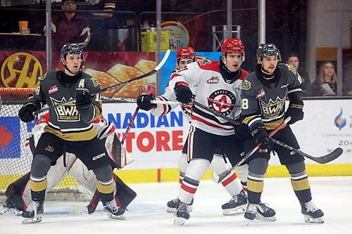 Rylen Roersma (18) and Matteo Michels (88) of the Brandon Wheat Kings and Moose Jaw Warriors defenceman Aiden Ziprick (21) watch the puck in front of Warriors goaltender Jackson Unger (30) during the second period of Game 4 Wednesday night at Westoba Place. (Tim Smith/The Brandon Sun)
