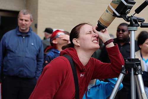 A young lady peers into a solar-filtered portable telescope outside the Brodie Science Building at BU to see the partial eclipse on Monday afternoon in Brandon. (Michele McDougall/The Brandon Sun)