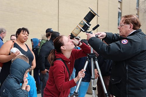 A young lady peers into a solar-filtered portable telescope outside the Brodie Science Building at BU to see the partial eclipse on Monday afternoon in Brandon. (Michele McDougall/The Brandon Sun)