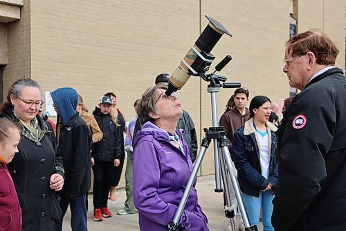 A lady peers into a solar-filtered portable telescope outside the Brodie Science Building at BU to see the partial eclipse on Monday afternoon in Brandon. (Michele McDougall/The Brandon Sun)
