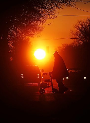 Silhouetted against the rising sun on the first day of the spring equinox, motorists wait at a stop light along Princess Avenue while a man with a walker crosses the street on Wednesday morning. (Matt Goerzen/The Brandon Sun). 