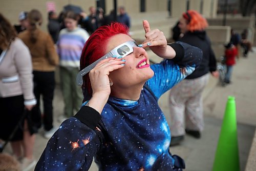 08042024
Aleca Antonakis peers at the solar eclipse through special glasses as the sun and passing moon poke through cloud cover over Brandon on Monday afternoon during a viewing party for the celestial event at Brandon University. 
(Tim Smith/The Brandon Sun)