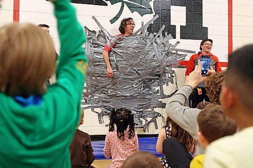 Students at École Harrison celebrate after duct-taping vice-principal Shawn Lehman to the gymnasium wall during an assembly fundraiser for the family of Jesse Olson on Tuesday. (Tim Smith/The Brandon Sun)
