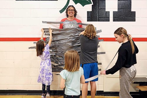 09042024
Students at &#xc9;cole Harrison duct-tape vice principal Shawn Lehman to the gymnasium wall during an assembly fundraiser for the family of eleven-year-old grade-six student Jesse Olson on Tuesday. After a battle with cancer, Olson is now cancer-free and the school sold strips of duck-tape to stick Lehman to the wall as a way of raising funds for Olson&#x2019;s family. Students also donated for the chance to be picked to pie staff members with whip-cream pies during the assembly. 
(Tim Smith/The Brandon Sun)