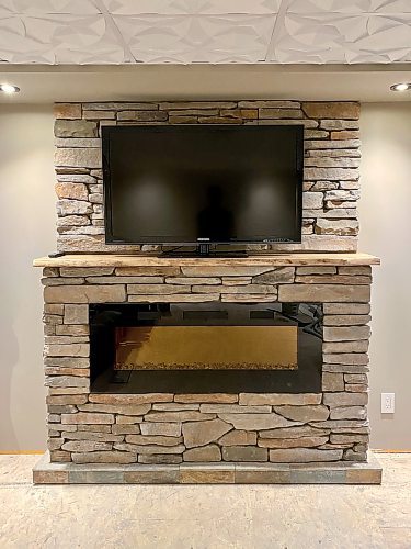 Photos by Marc LaBossiere / Free Press
Completed feature structure sheathed in cultured stone includes a 50-inch electric fireplace inset below a live-edge mantle, with TV above.  