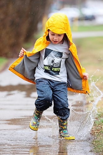 Four-year-old Kieran MacMillan plays in a puddle outside his home in Minnedosa on a rainy Thursday afternoon. (Tim Smith/The Brandon Sun)