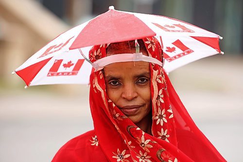 Atsdee Ygizaw stays dry under an umbrella hat that matches the rest of her outfit while waiting for a bus on Princess Avenue on a rainy Tuesday. (Tim Smith/The Brandon Sun)