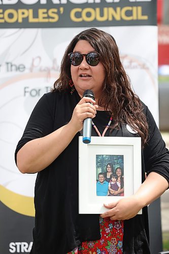 Natashia Marion, an Indigenous community coordinator with the Brandon Urban Aboriginal Peoples' Council, holds a picture of the women in her family while addressing participants in the Moose Hide Campaign march from Princess Park on Thursday afternoon. (Matt Goerzen/The Brandon Sun)