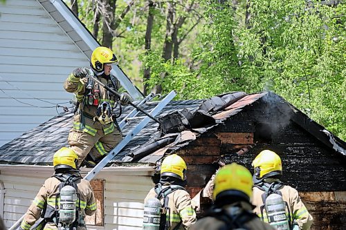 A firefighter exposes hot spots on a burning shed early Sunday afternoon. (Colin Slark/The Brandon Sun)