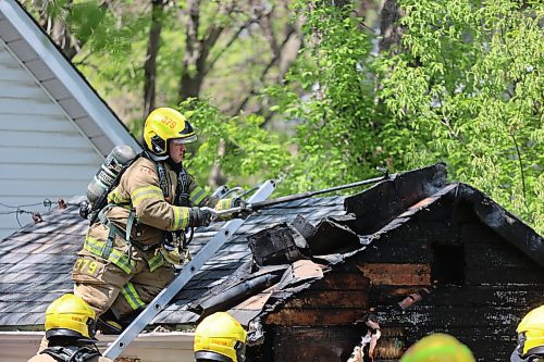 A firefighter exposes hot spots on a burning shed early Sunday afternoon. (Colin Slark/The Brandon Sun)