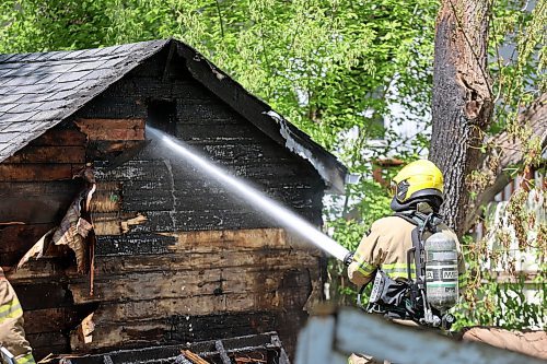 A firefighter pours water onto a burning shed in a backyard near the intersection of 12th Street North and Stickney Avenue early Sunday afternoon. (Colin Slark/The Brandon Sun)