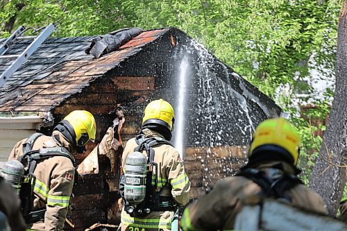 A firefighter pours water onto a burning shed in a backyard near the intersection of 12th Street North and Stickney Avenue early Sunday afternoon. (Colin Slark/The Brandon Sun)