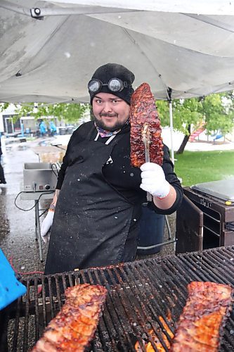 Buckey BBQ griller Brad Bosence holds up a rack of ribs while manning an outdoor grill at the Riverbank Discovery Centre on Friday afternoon as snow falls around him. (Matt Goerzen/The Brandon Sun)